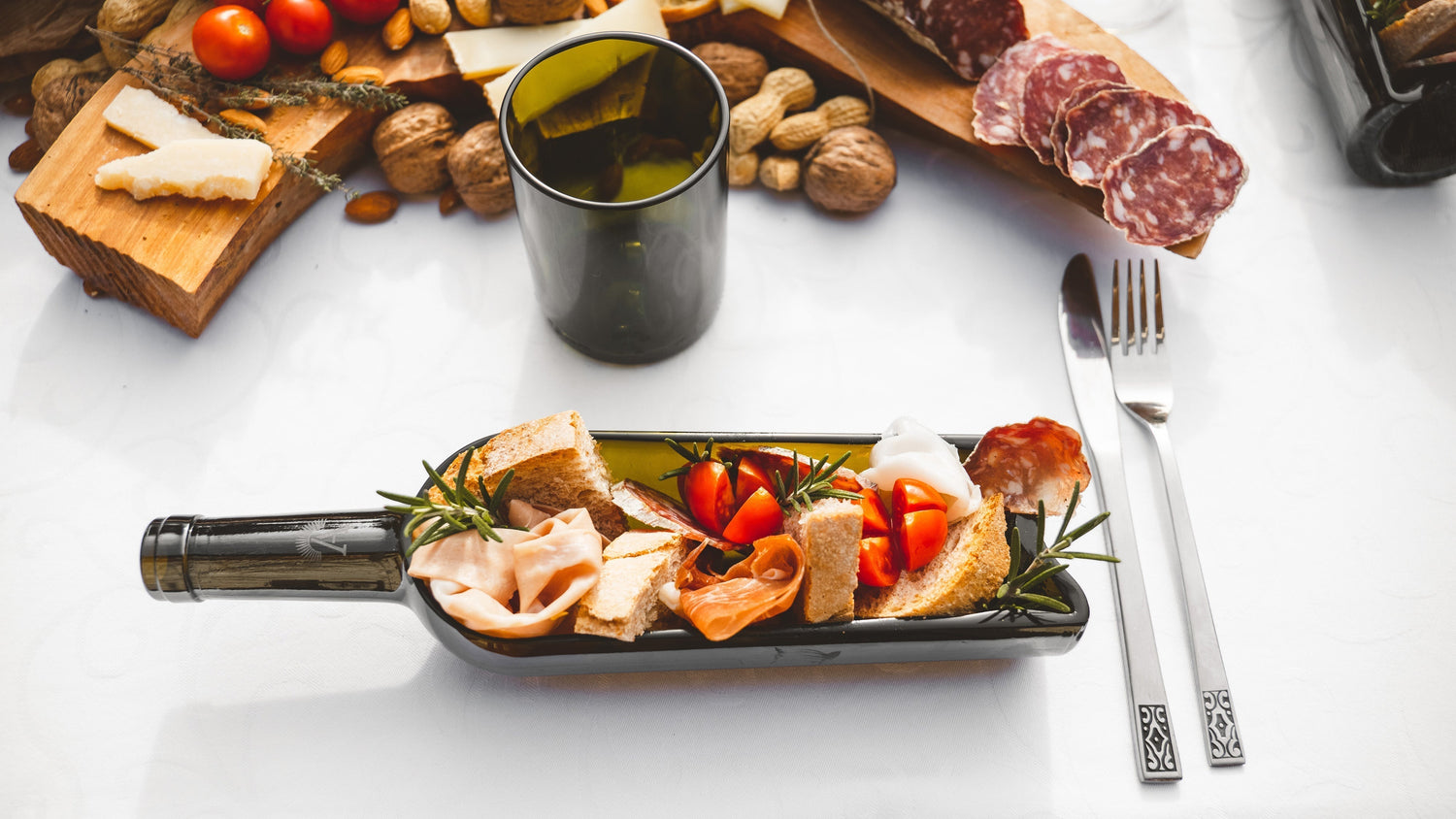 tavola apparecchiata con piatto e bicchiere in vetro riciclato da amarzo con affettati e bontà tipiche toscane