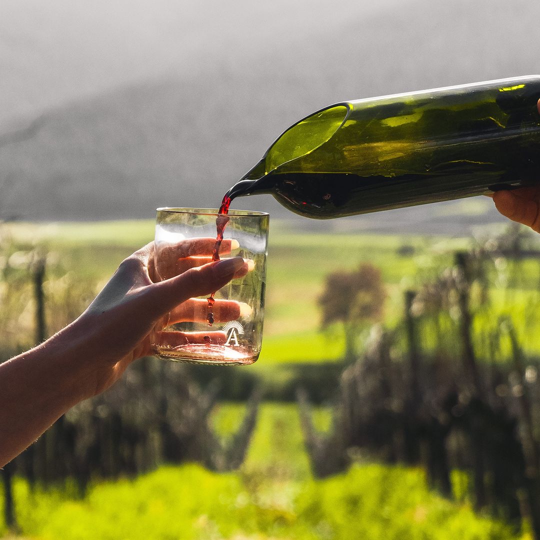 Bottiglia di vetro riciclato che versa vino toscano